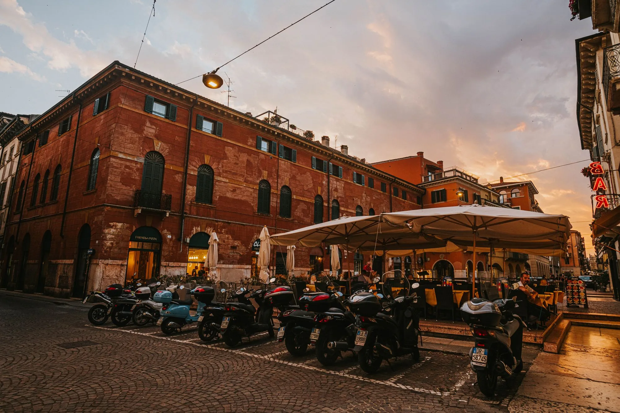 Italiaans plein in de avond met een terras en geparkeerde scooters
