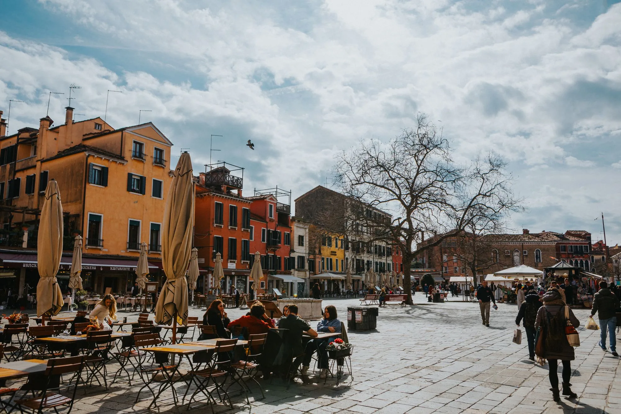 Mensen op het terras van een café aan een zonnig Italiaans plein