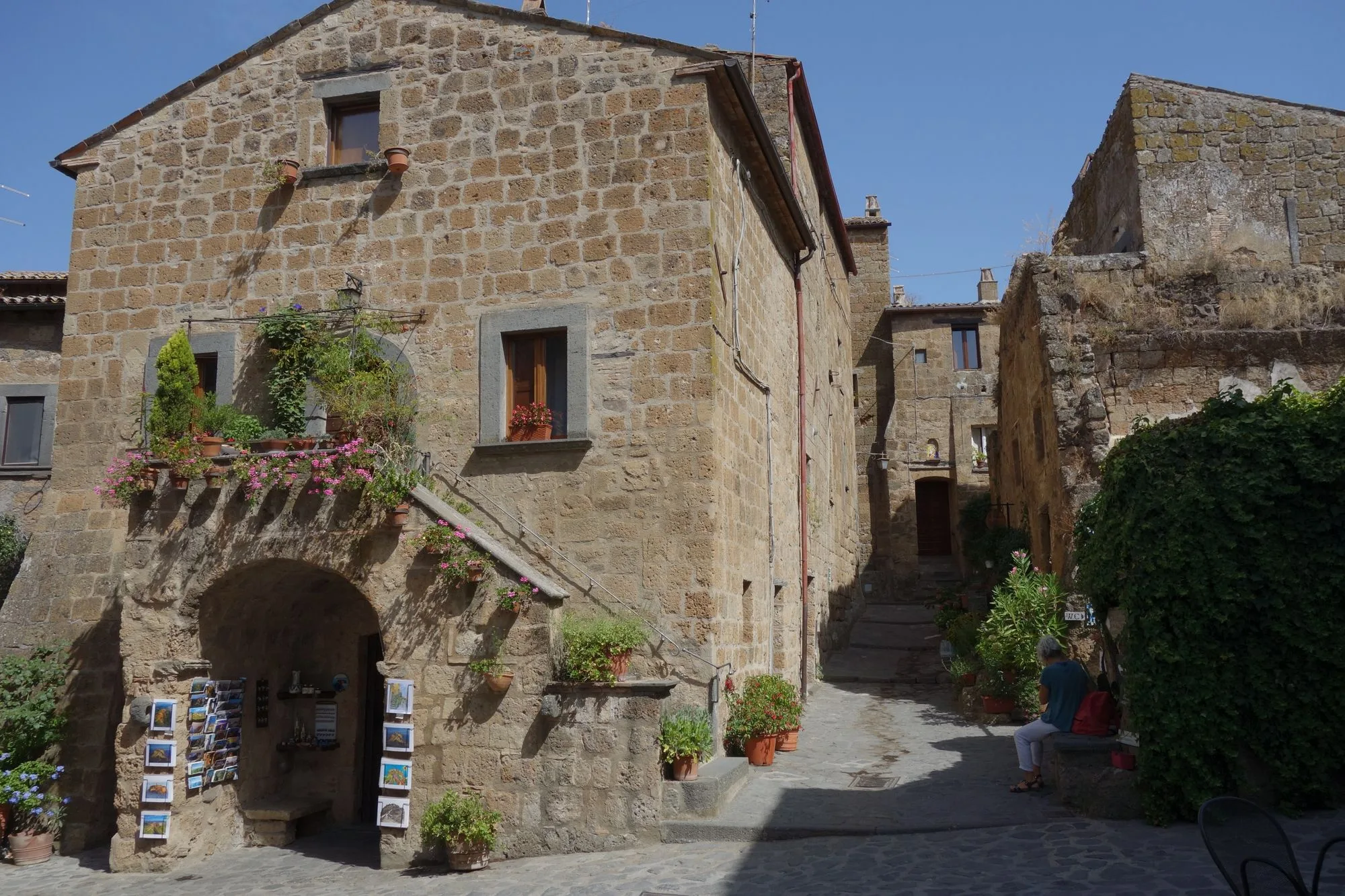 Smal steegje met een oud stenen huis en bloemen in een Italiaans dorp