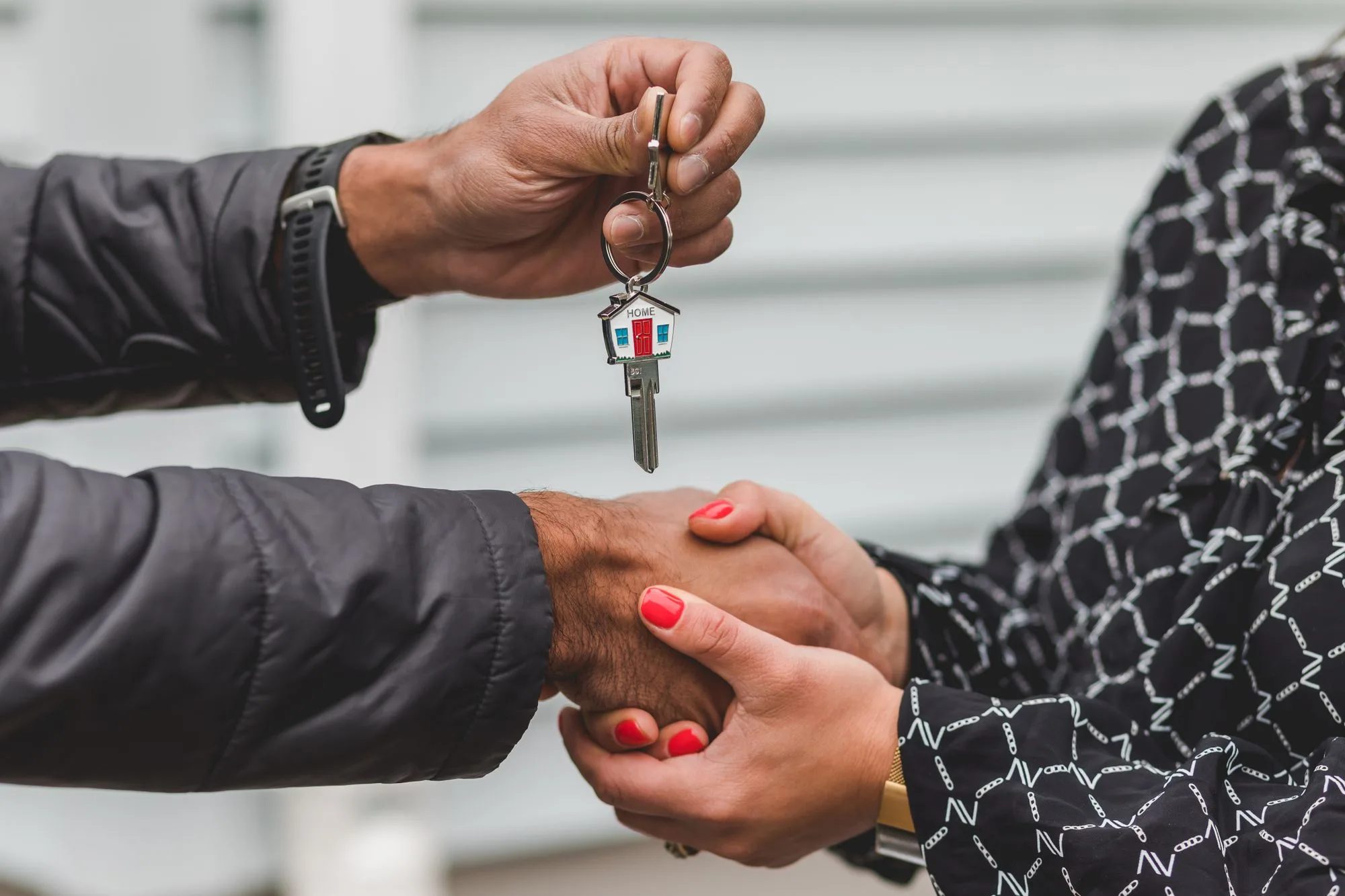 Een makelaar overhandigt de sleutels van een woning aan een nieuwe eigenaar