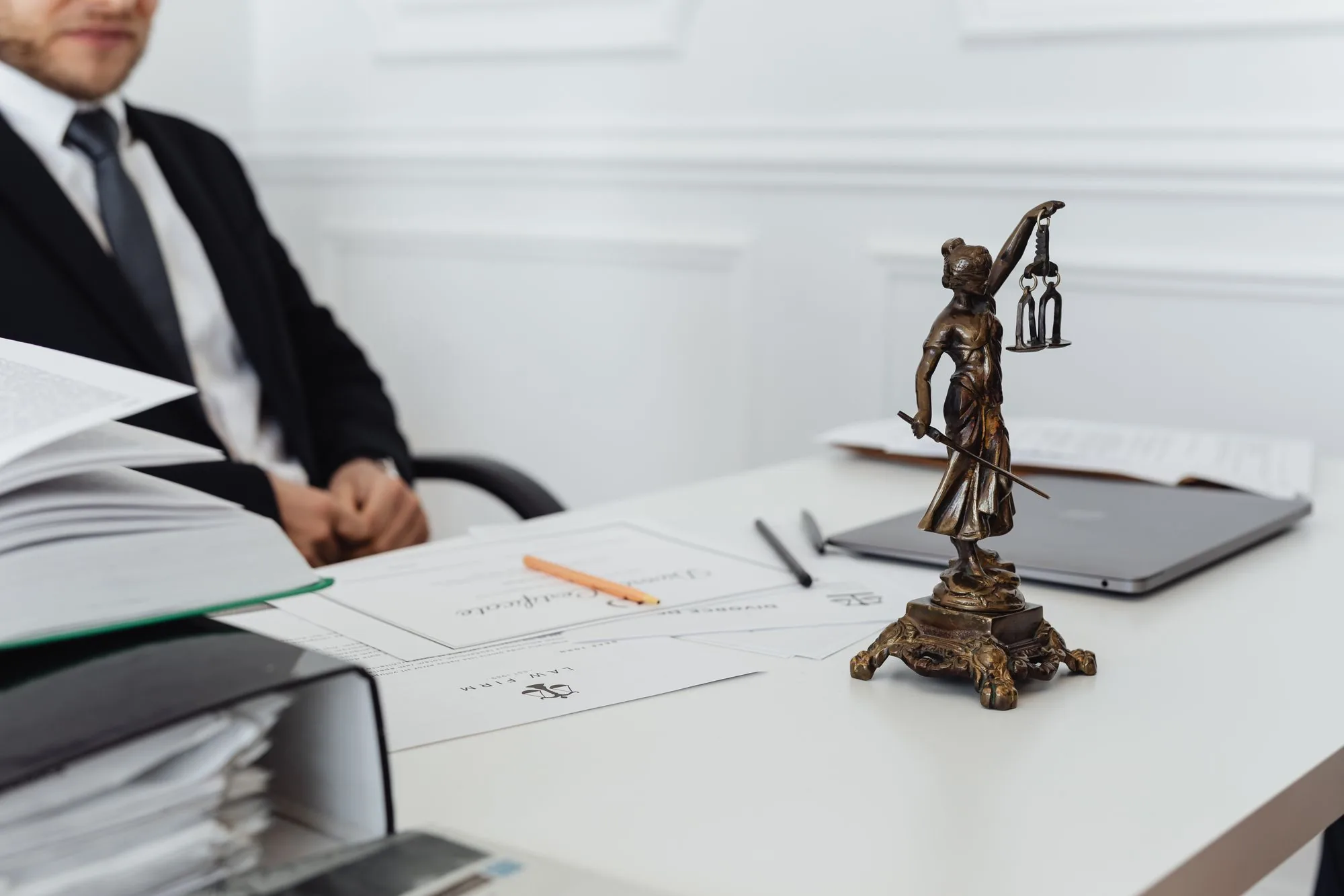 Kantoorbureau met documenten en een beeldje van Vrouwe Justitia