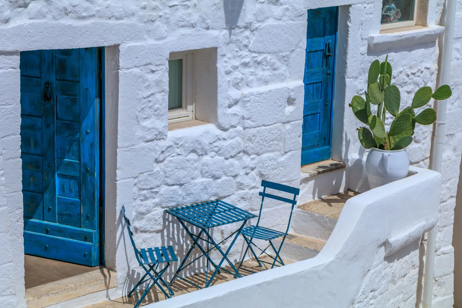 Terras met blauwe deuren en cactussen in Ostuni